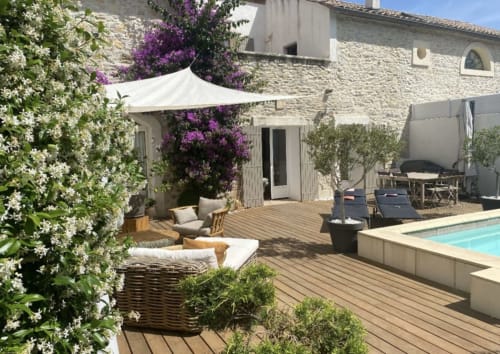Patio luxueux avec piscine, voile blanche, bougainvillées fleuries et architecture en pierre à La Conciergerie De Franck,
