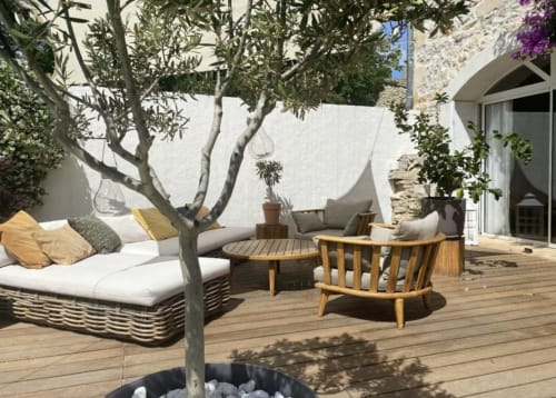 Mediterraner Patio der La Conciergerie De Franck mit Olivenbaum, Loungebereich, Holzterrasse und Steinmauern in Boissières
