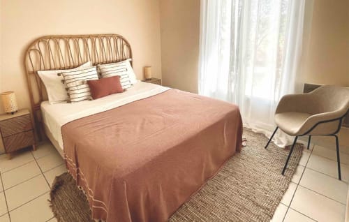 Schlafzimmer der Villa Moka in La Conciergerie De Franck mit Rattanbett, gestreiften Kissen und Gartenblick in Boissières