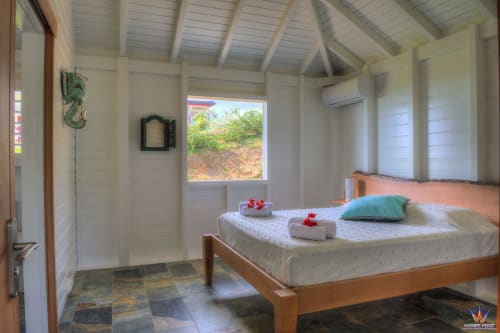 Bright bedroom in Kaz'Quisqualis cottage at Le Domaine De L'ilet, Saint-Claude with wooden bed, window view, and modern