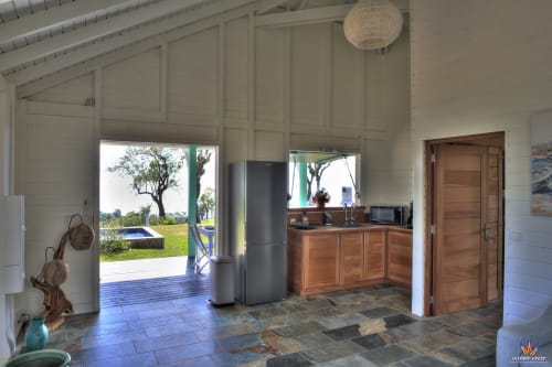 Modern cottage kitchen at Le Domaine De L'ilet in Saint-Claude with sea views, wooden cabinetry, and open patio access