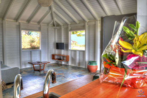 Bright cottage interior at Le Domaine De L'ilet with white beamed ceilings, sea views, sitting area, and colorful flowers in