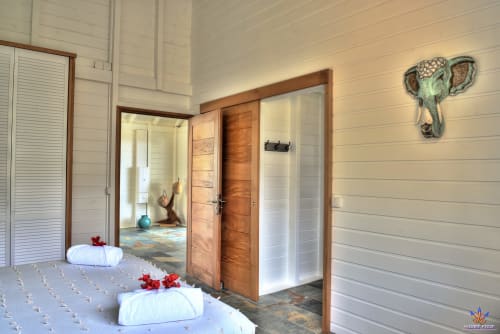 Spa bathroom at Le Domaine De L'ilet cottage in Saint-Claude with towels, wooden doors, and elephant decor