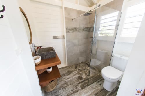 Modern bathroom with walk-in shower, stone vessel sink, and toilet at Le Domaine De L'ilet cottage in Saint-Claude,