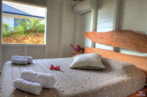 Bright cottage bedroom at Le Domaine De L'ilet with wooden bed frame, white linens, rolled towels, and garden view window in