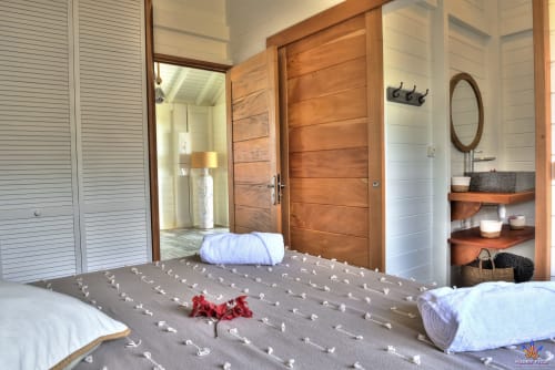 Bedroom in Kaz'Mussaenda cottage at Le Domaine De L'ilet, Guadeloupe, with wooden doors and ensuite bathroom