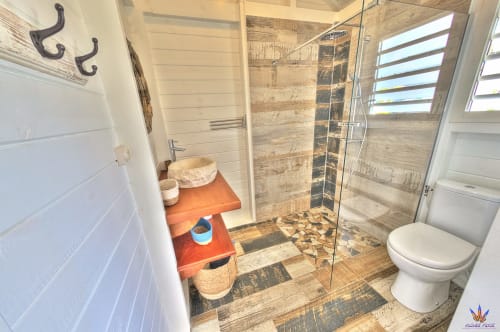 Modern bathroom with walk-in shower, toilet, and orange vanity at Le Domaine De L'ilet cottage in Saint-Claude, Guadeloupe