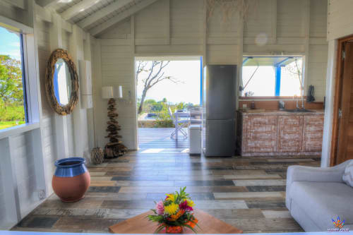 Bright open-plan cottage living area at Le Domaine De L'ilet with sea views, kitchenette, white walls, and tropical décor