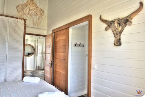 Rustic cottage bedroom at Le Domaine De L'ilet with wooden doors, white shiplap walls, and longhorn skull décor in