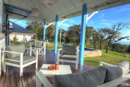 Tropical patio with blue pergola, comfortable seating, and ocean views at Le Domaine De L'ilet cottage in Guadeloupe
