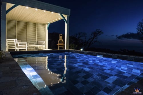 Illuminated poolside cottage at Le Domaine De L'ilet with sea view at dusk in Saint-Claude, Guadeloupe