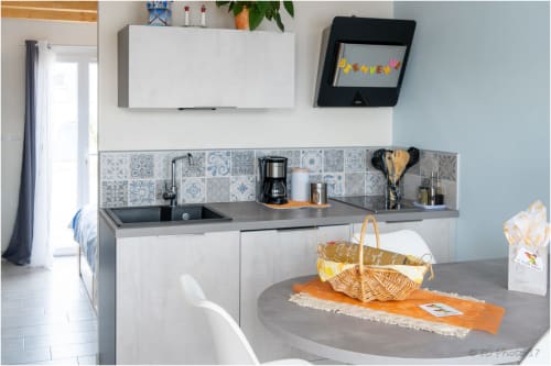 Cuisine moderne au gîte Le Pirate Benèze à Trizay avec armoires blanches, dosseret carrelage bleu et table ronde