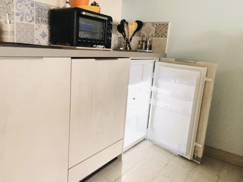 Kitchenette du Pirate Benèze à Trizay : meubles blancs, réfrigérateur ouvert et petits appareils