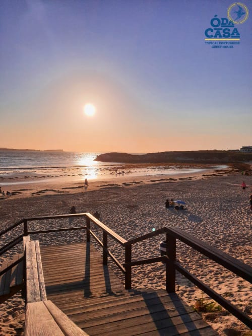 Vue du coucher de soleil sur la plage de la maison d'hôtes Ó da Casa à Peniche, Portugal avec accès par promenade en bois