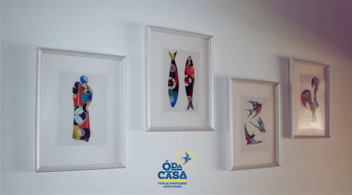 Quatre textiles encadrés avec motifs colorés d'oiseaux et de poissons exposés au mur blanc de la maison d'hôtes Ó da Casa à Peniche,