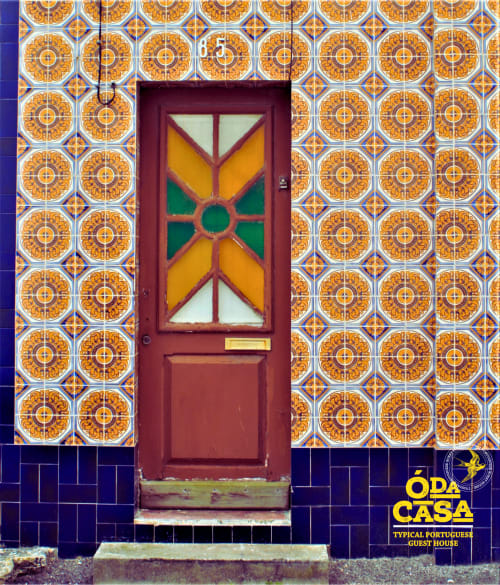 Porte rouge avec fenêtre géométrique colorée à la maison d'hôtes Ó da Casa à Peniche, Portugal, entourée d'ornements traditionnels