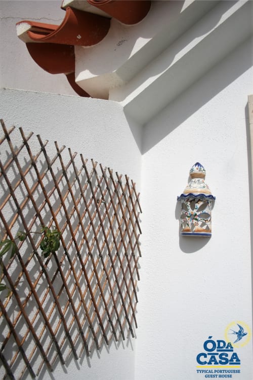 Mur blanchi à la chaux à la pension Ó da Casa à Peniche avec carrelage portugais bleu et blanc, treillis décoratif