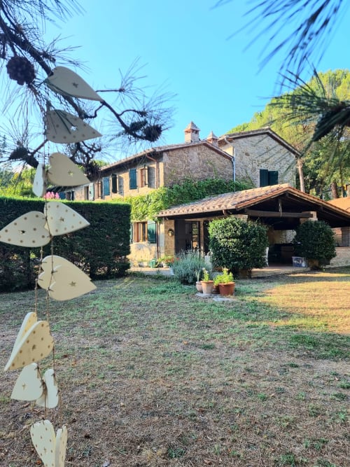 Tuscan villa courtyard with stone architecture, wooden pergola, palm trees, and cactus garden under clear blue sky