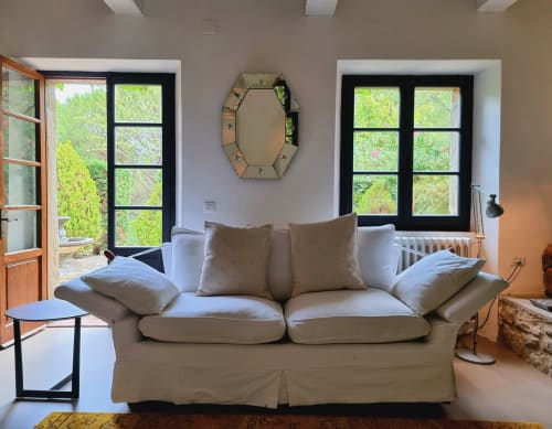 Bright living room with cream sofa, large windows overlooking greenery, octagonal mirror, and modern furnishings at Secret