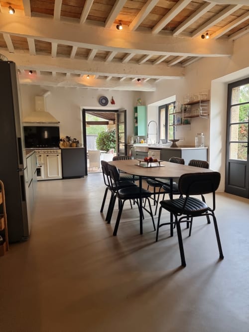 Modern villa dining and kitchen area with wooden beamed ceiling, black chairs, and garden view doors