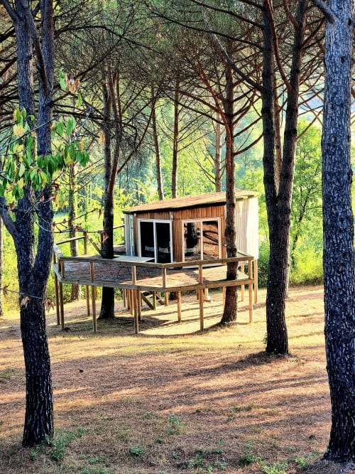 Wooden tree house villa nestled among pine trees with deck and glass doors at Villa Italia Management