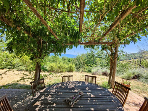 Shaded outdoor dining terrace with sea views at Villa Italia, overlooking Mediterranean landscape