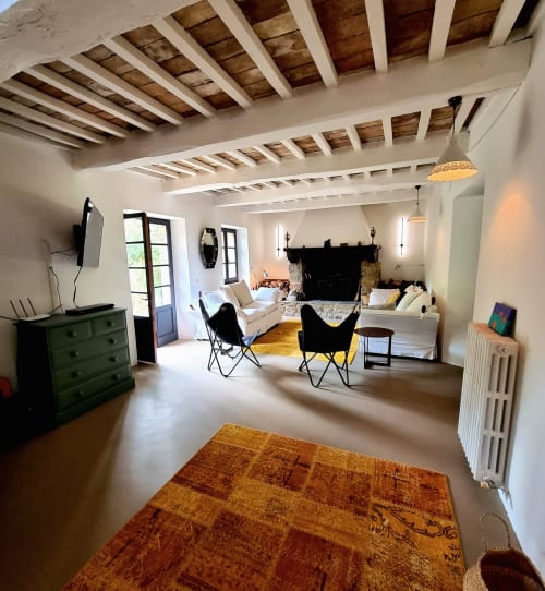 Spacious loft-style living room with exposed wooden beams, fireplace, black butterfly chairs, and terracotta rug at Villa
