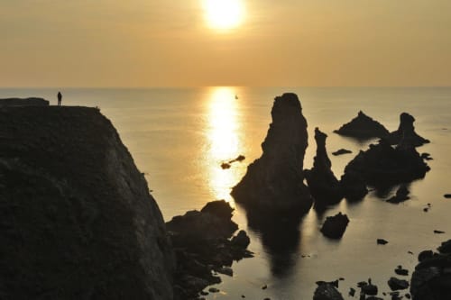 Coucher de soleil dramatique sur la côte rocheuse de Belle-Île-en-Mer avec silhouettes d'arches et falaises marines