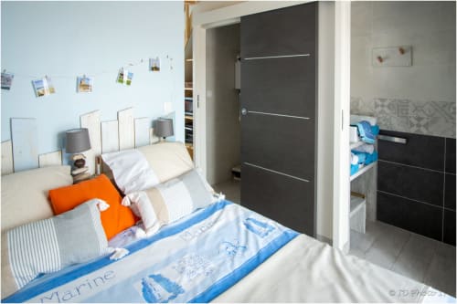 Chambre moderne au Pirate Benèze à Trizay avec literie bleu marine, coussin orange et décoration contemporaine