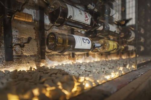 Wine bottles displayed in rustic rack with ambient lighting at Three Little Pigs hotel, Blandford Forum