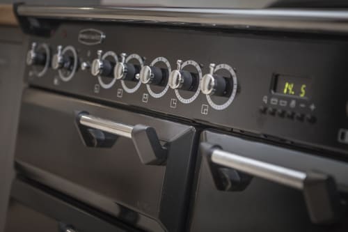 Cucina elettrica nera con più manopole di controllo e porte del forno all'hotel Three Little Pigs, Blandford Forum