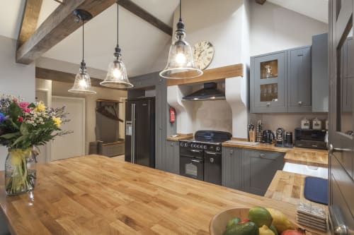 Cucina moderna con isola in legno, armadi grigi, fornello nero e lampade a sospensione all'hotel Three Little Pigs