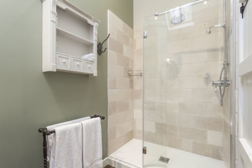 Moderna cabina doccia con rivestimento in piastrelle beige e parete in vetro nel bagno dell'hotel Three Little Pigs, Blandford Forum