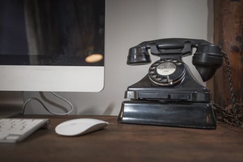 Telefono a disco vintage nero alla scrivania dell'hotel Three Little Pigs a Blandford Forum con mouse del computer moderno