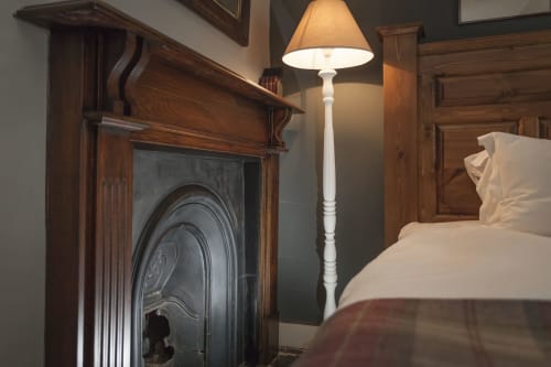 Elegante camera da letto dell'hotel Three Little Pigs a Blandford Forum con camino, lampada a stelo e arredi in legno