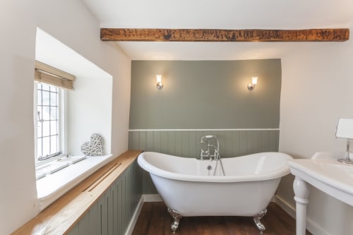 Bagno di lusso dell'hotel Three Little Pigs a Blandford Forum con vasca indipendente, rivestimenti verdi e finestra.