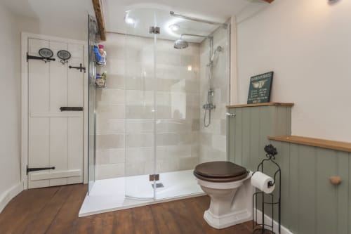 Bagno moderno all'hotel Three Little Pigs con doccia walk-in, WC vintage, pavimento in legno e pareti rivestite di verde