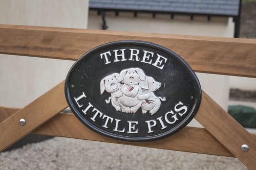 Insegna del pub Three Little Pigs con tre maialini bianchi su placca ovale nera, Blandford Forum