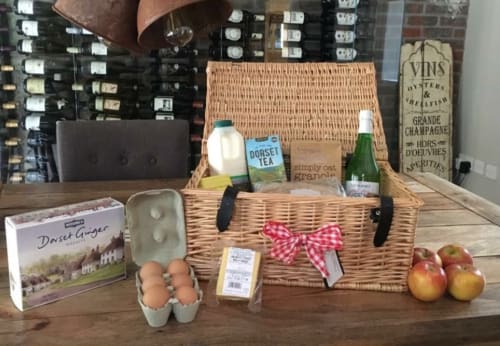 Cesto da picnic in vimini con tè Dorset, champagne, uova, mele e granola presso l'hotel Three Little Pigs di Blandford Forum
