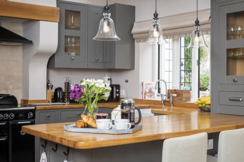 Cucina moderna presso l'hotel Three Little Pigs a Blandford Forum con armadi grigi, isola in legno e lampade a sospensione