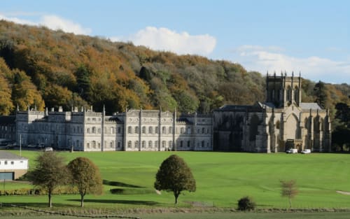 Stately stone manor with church overlooking manicured grounds near Blandford Forum