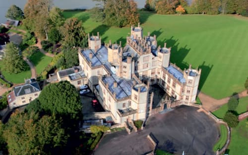Aerial view of Three Little Pigs castle hotel surrounded by lush grounds near Blandford Forum, England