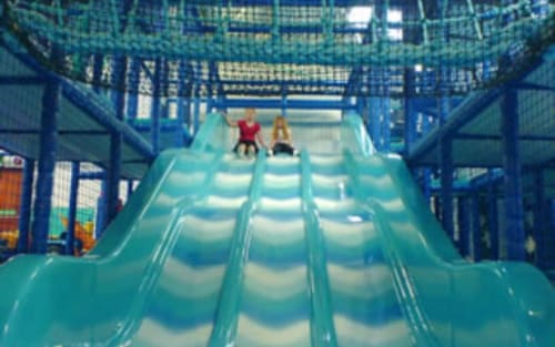 Turquoise indoor water slide at Three Little Pigs hotel in Blandford Forum with children sliding down