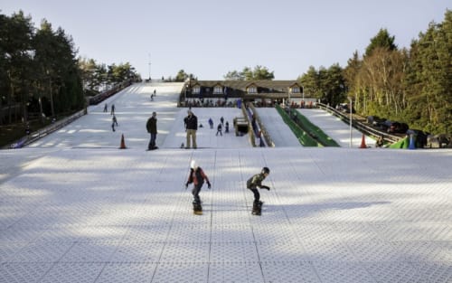 Indoor ski slope at Three Little Pigs near Blandford Forum with skiers on white mat surface and lodge building