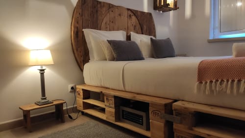 Modern bedroom at Casa d'Amélia Polo 2 in Obidos with pallet bed frame, white linens, wooden headboard, and bedside lamp