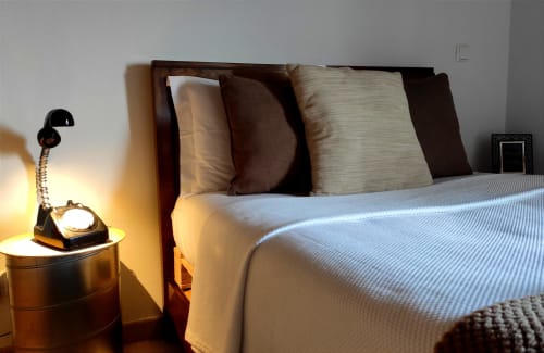 Quarto da vila Kindnessmoon em Óbidos com cama de madeira, almofadas, roupa de cama clara, luminária vintage de telefone no criado-mudo