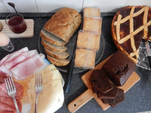 B&B Eleonora D'Arborea breakfast spread with sliced bread, pastries, cured meats, and chocolate cake in Posada