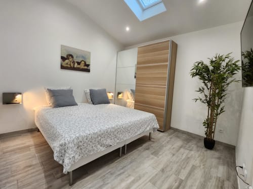 Modern bedroom at Domaine à l'Aise cottage in Saint-Pargoire with queen bed, wooden wardrobe, skylights, and garden views