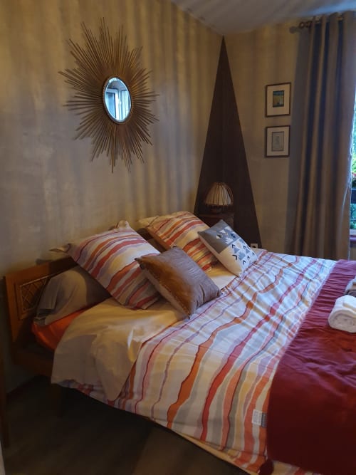 Chambre douillette aux Forges Du Lou avec literie rayée, miroir soleil et baldaquin en bois foncé à Jugon-les-Lacs, France