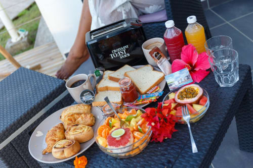 Petit-déjeuner gourmand au Kaz A Bibi BnB à Sainte-Rose : croissants, fruits frais, jus et café sur table en terrasse